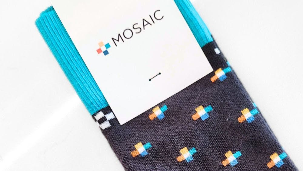 Custom socks with a repeating logo pattern on a grey background for solar energy company Mosaic