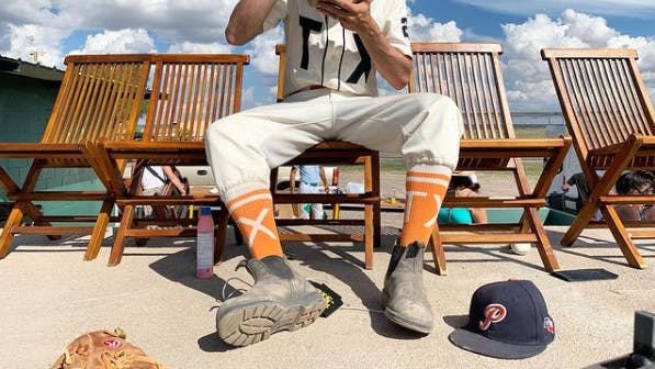 Player wearing orange custom baseball socks for Texas Playboys 