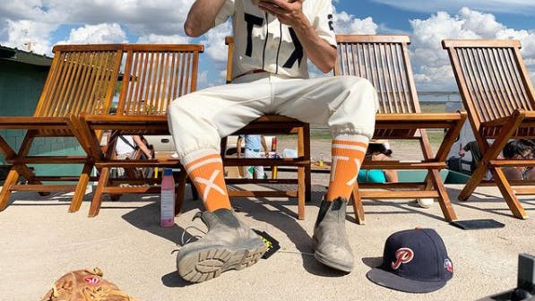 Player wearing orange custom baseball socks for Texas Playboys