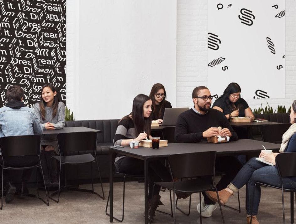 The SquareSpace office in New York, showing the modern black and white cafeteria with a variety of happy employees eating lunch