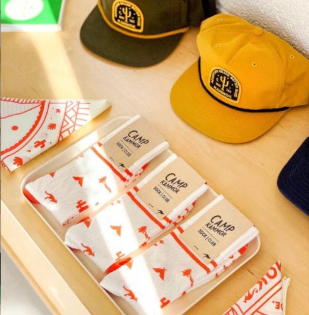 The Camp Kammok company store showing branded merchandise such as hats, bandanas, and custom socks the Kammok designed for its Camp Kammok event