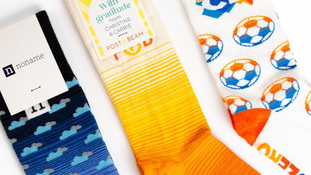 Custom socks with gradients knit into them showing a blue gradient, orange gradient, and blue to orange gradient in a soccer ball pattern