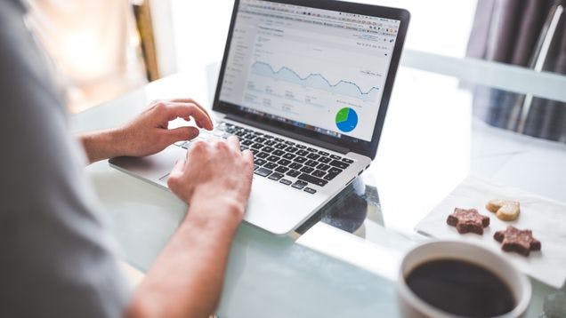 Man working on a laptop on his desk checking the traffic analytics from his company store