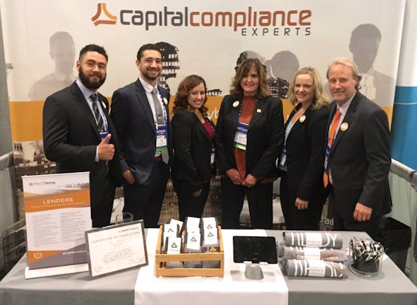 Capital Compliance team at trade show booth with custom sock giveaway items