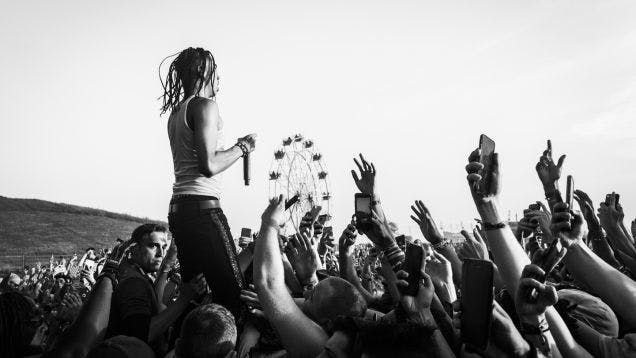 Black and white photo of an artist performing at Coachella in the middle of a large crowd