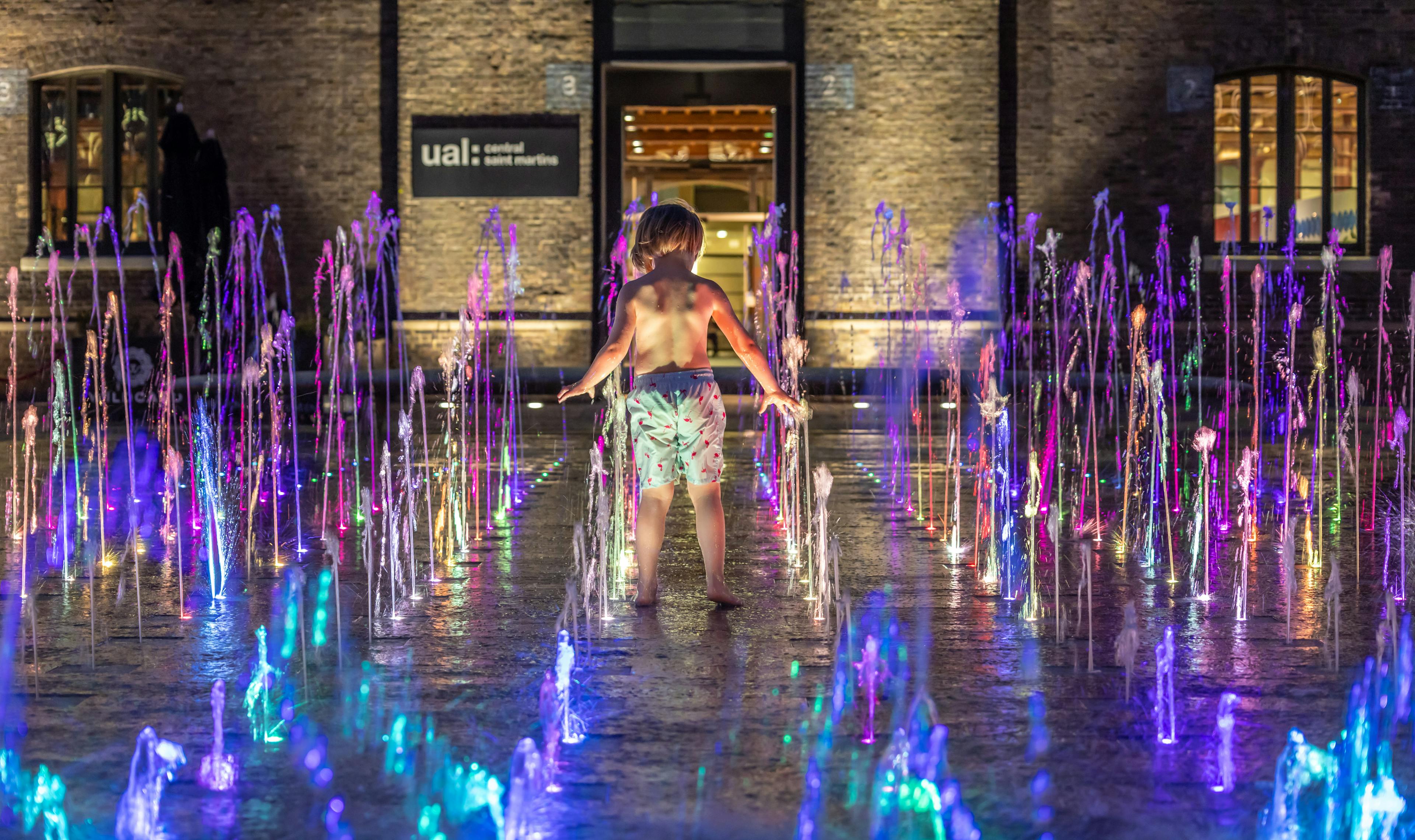 A child playing in the Granary Sq water fountain