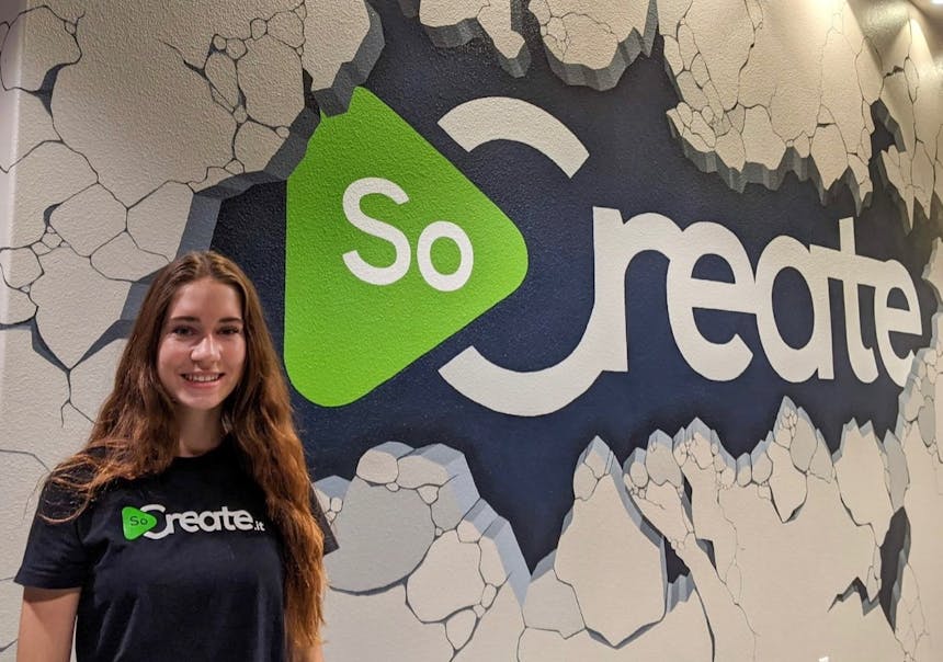 Athena Pruett vor der Wand mit dem SoCreate-Logo