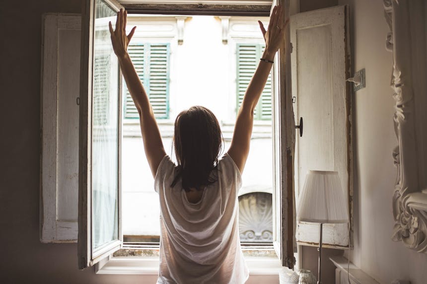 Screenwriter stretches upward in front of a window