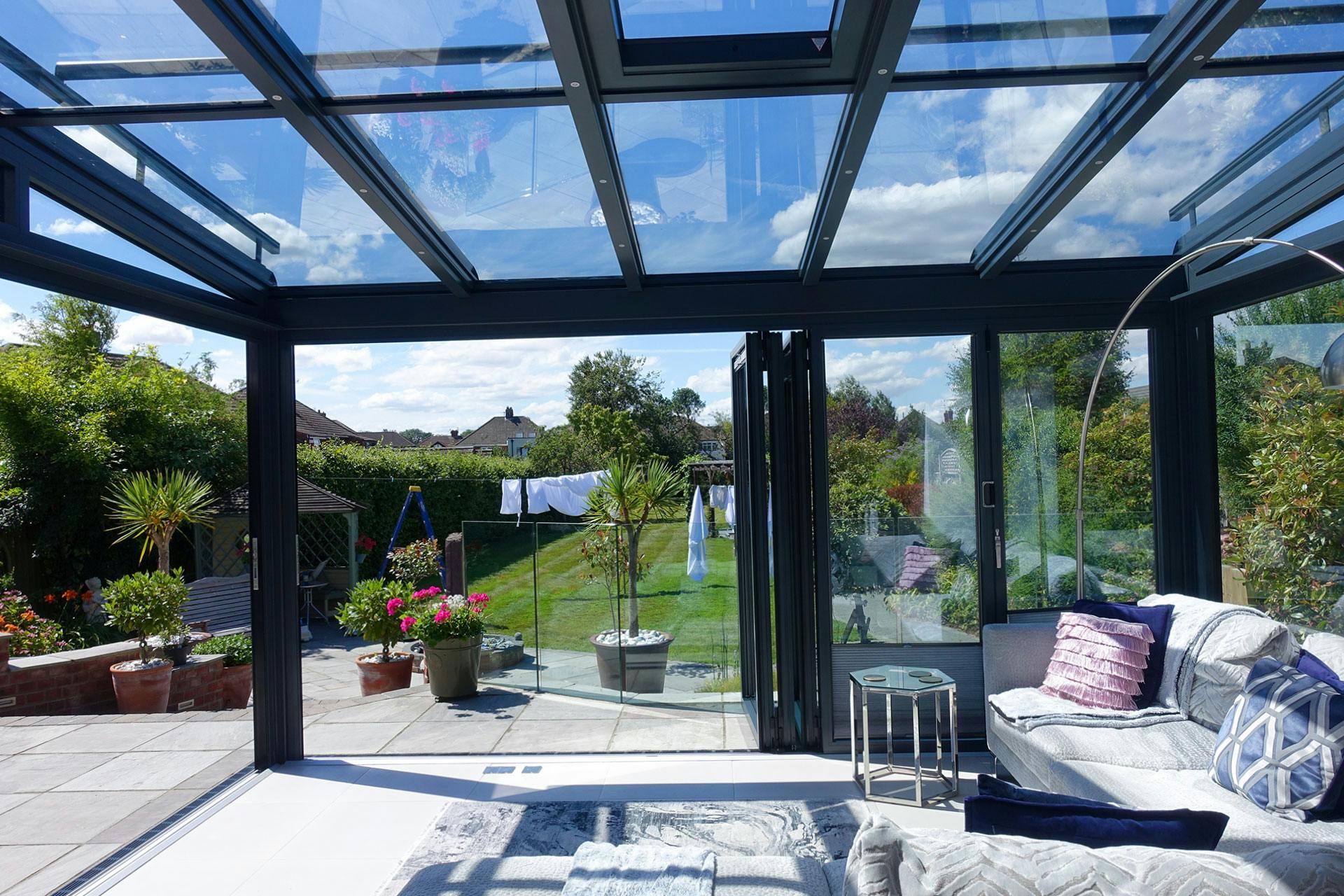 white sofa in glass garden room extension looking across garden on summer day