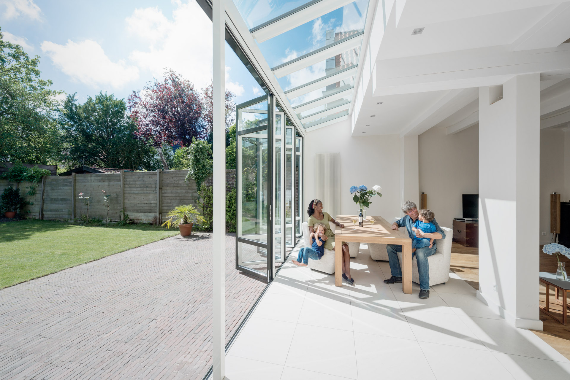 family sitting at a table in a glass conservatory with open doors