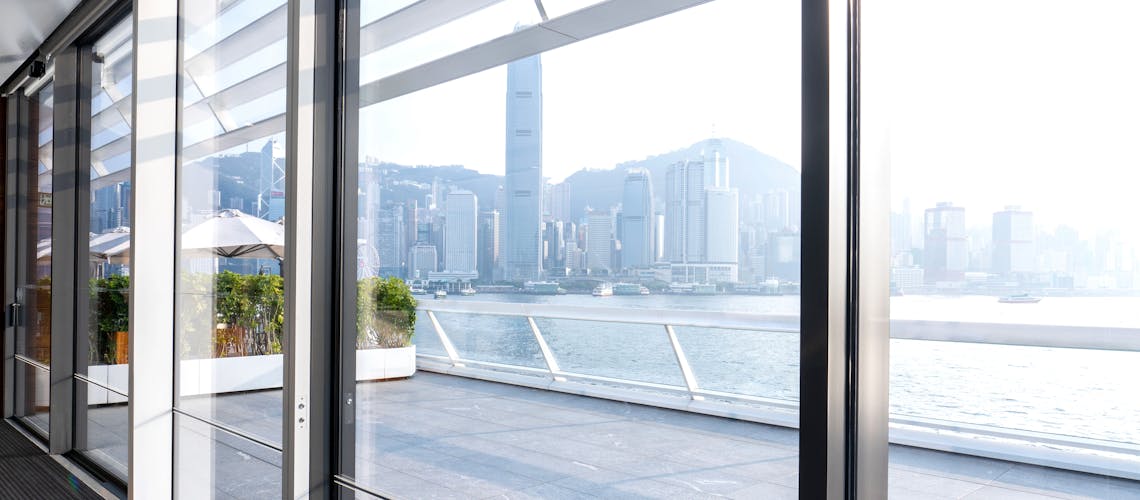View through large sliding glass doors to river and cityscape outside.