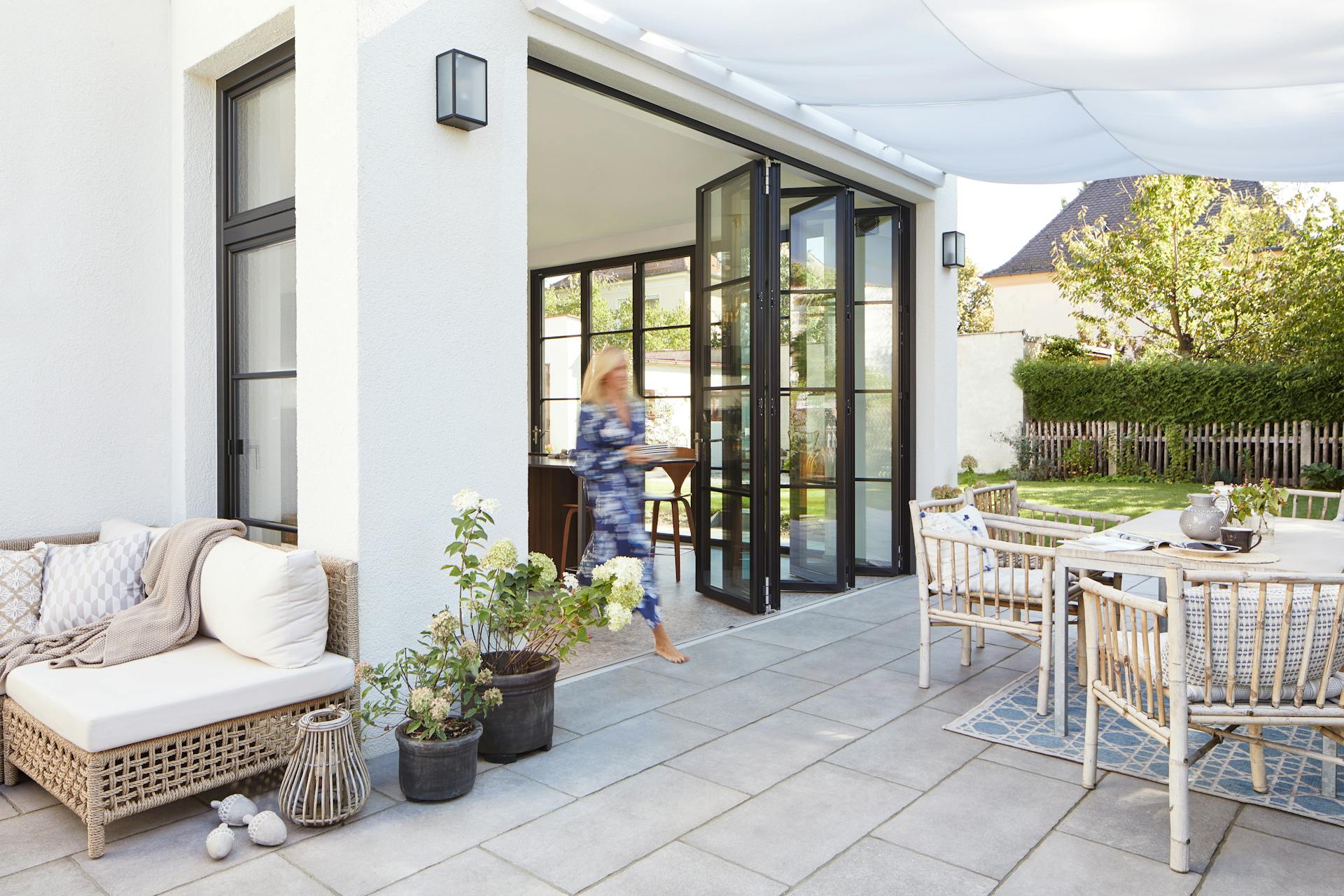 patio with white furniture and bifold doors to kitchen