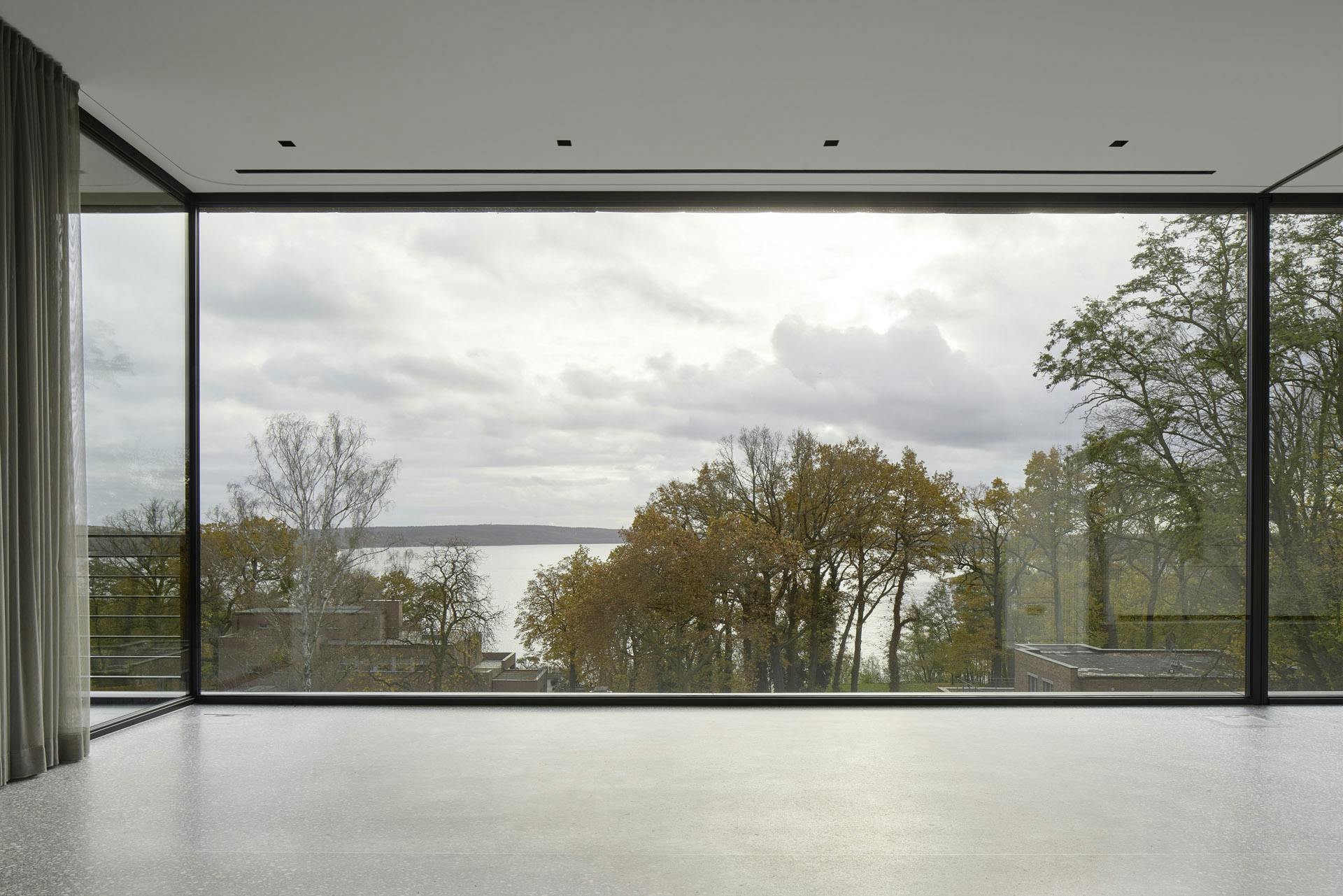 empty modern room with floor to ceiling sliding doors and views of trees on overcast day