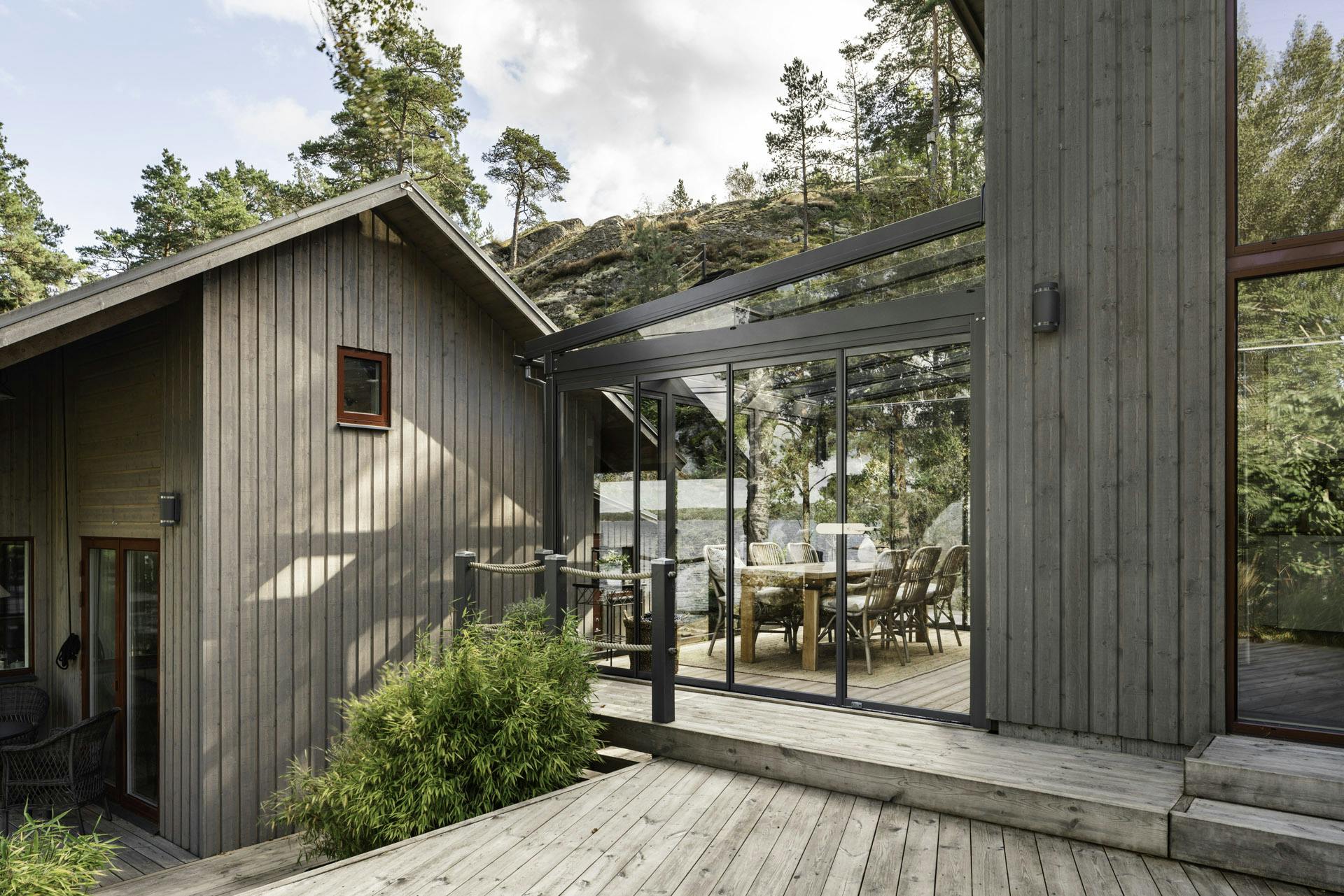 Glass room in wooded location with timber home