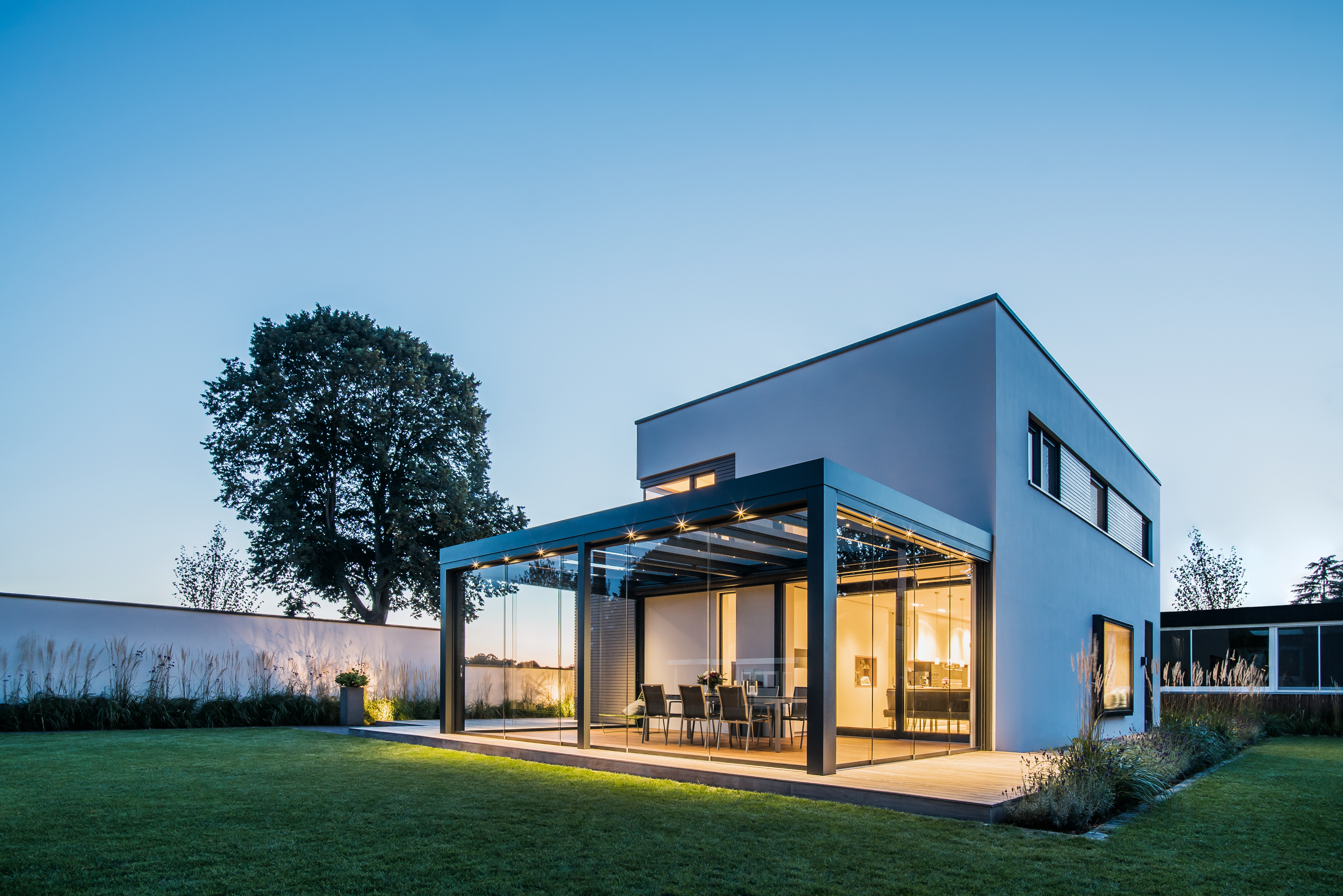 glass room on detached home illuminated on summer evening