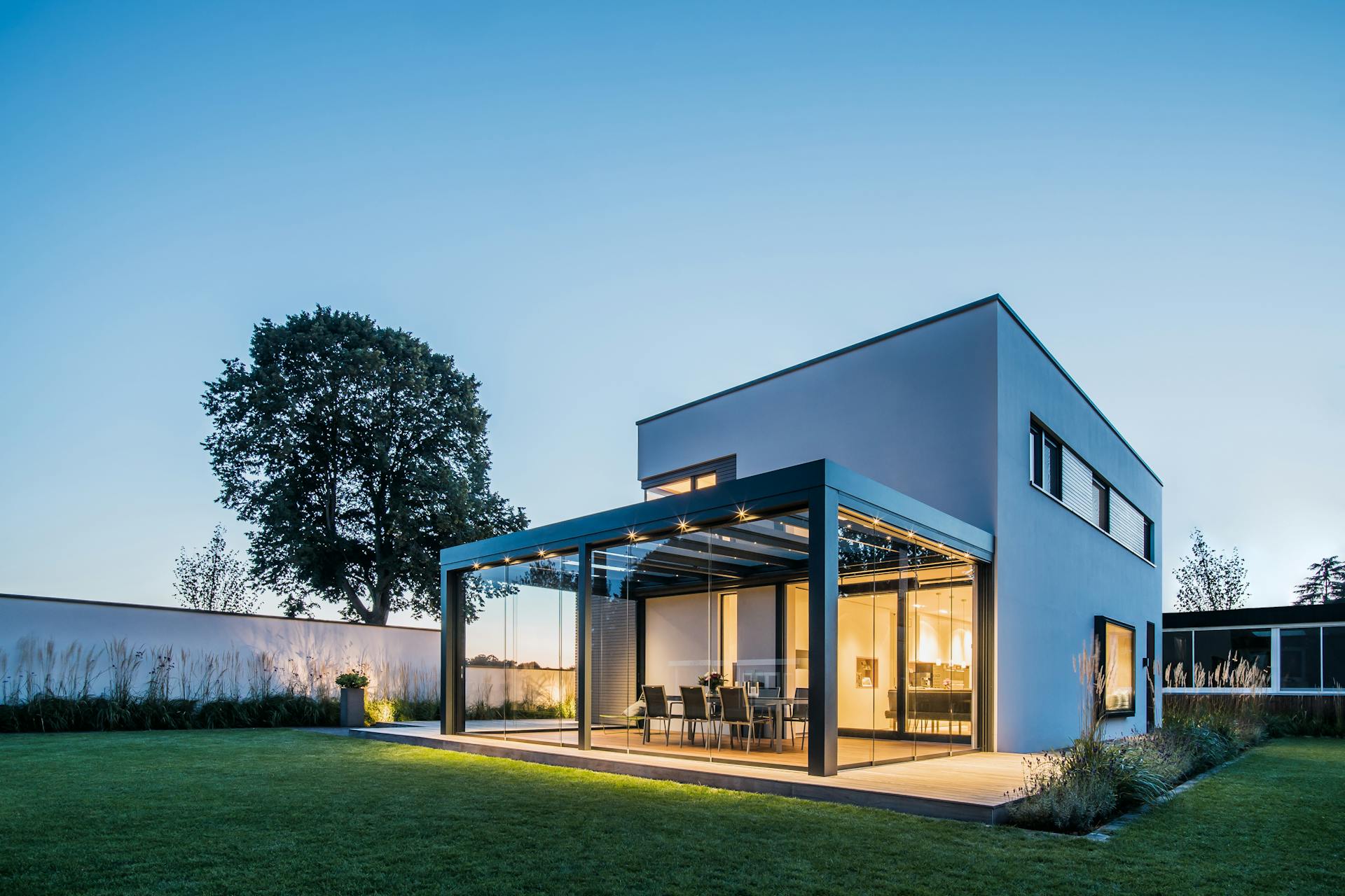 glass room on detached home illuminated on summer evening