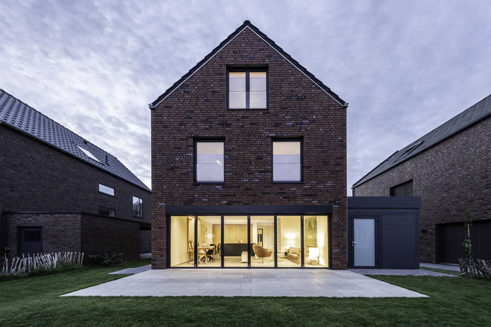 A view of a home at twilight from the rear showing closed bi-fold doors