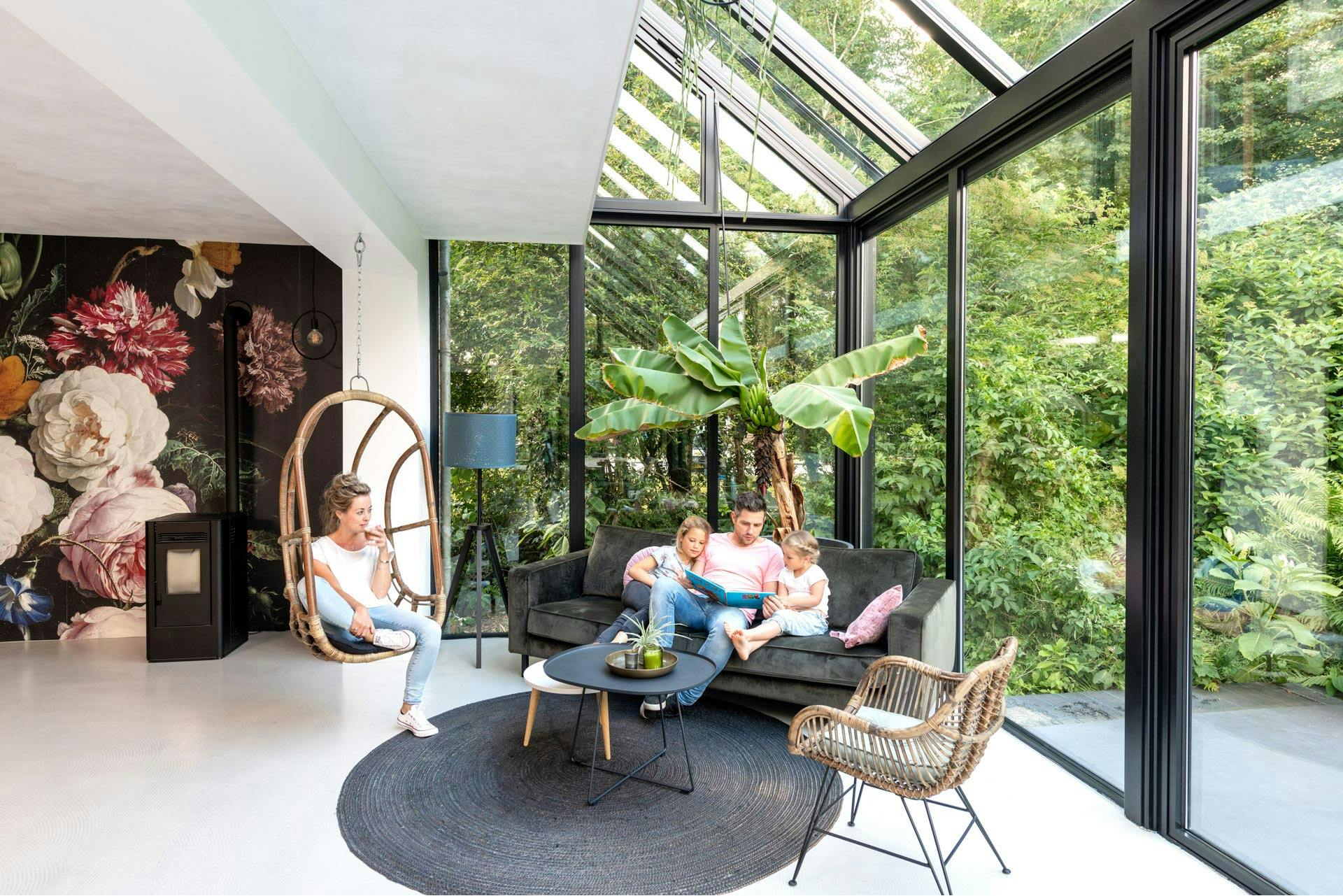 A glass home extension that is bright and airy with greenery outside