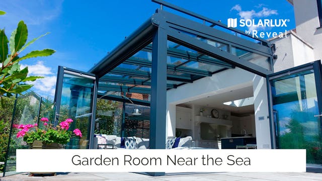 A glass garden room extension with summer flowers and bright blue sky