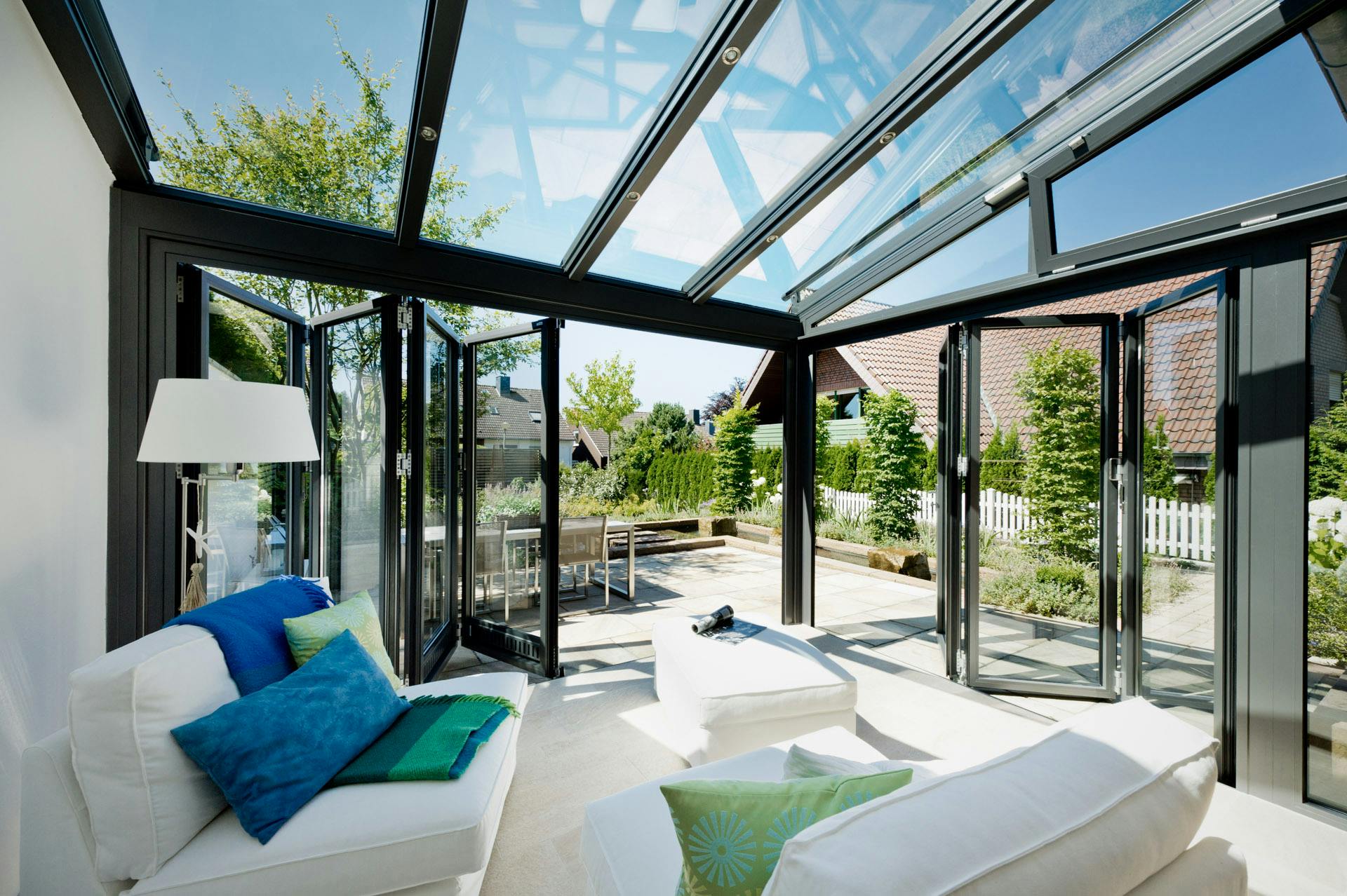 fully glazed living room extension with white sofa and green and blue soft furnishings