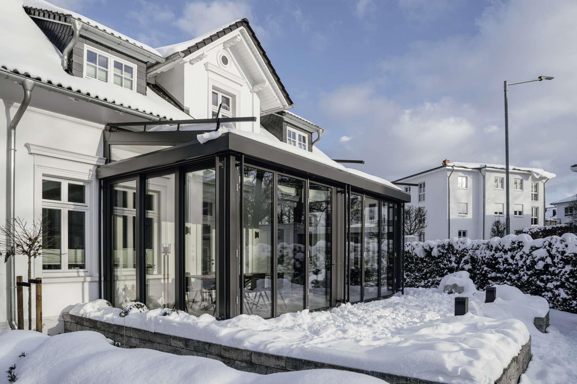Thick snow in the garden of a white townhouse with glass extension