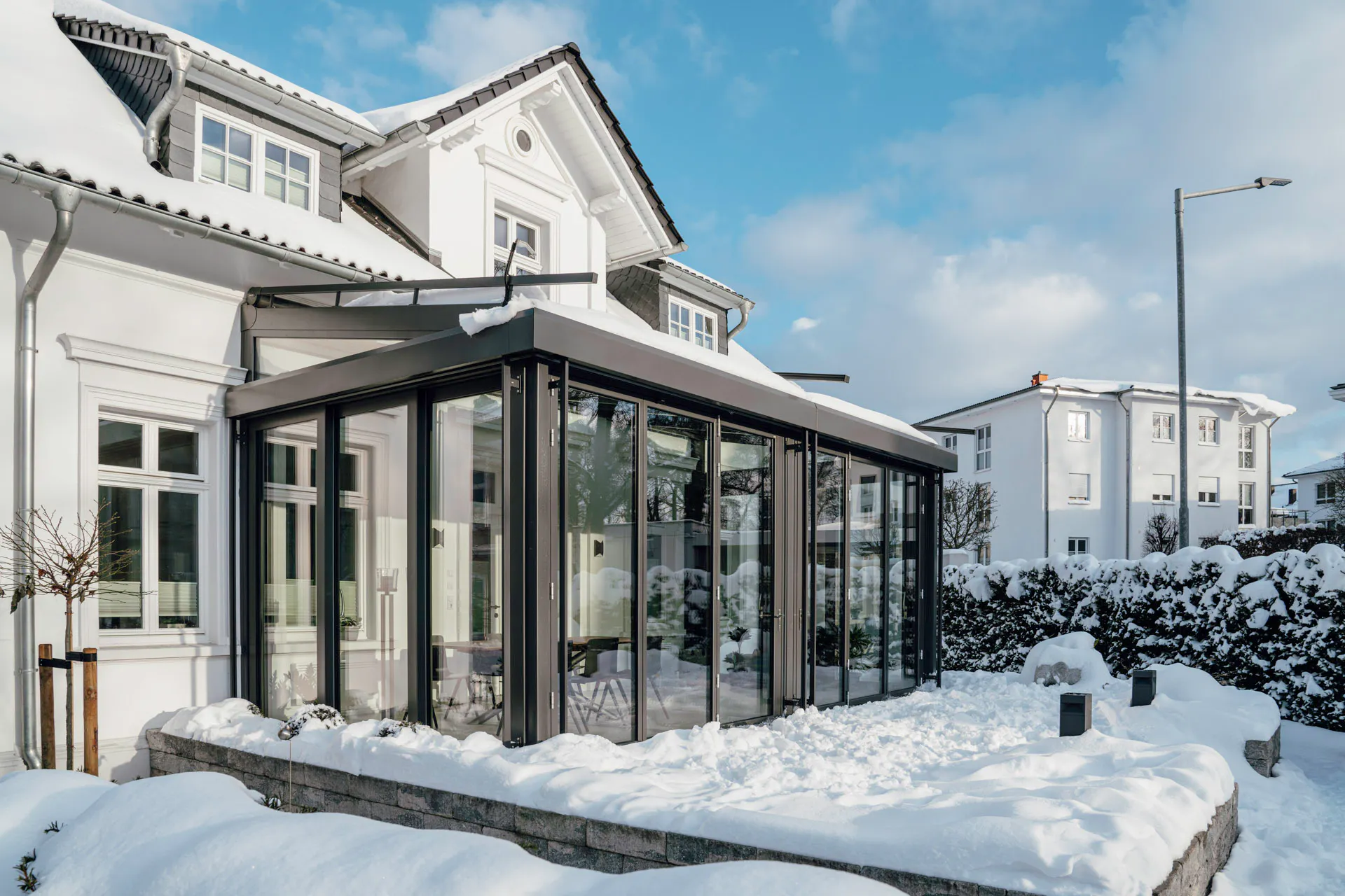 Thick snow in the garden of a white townhouse with glass extension