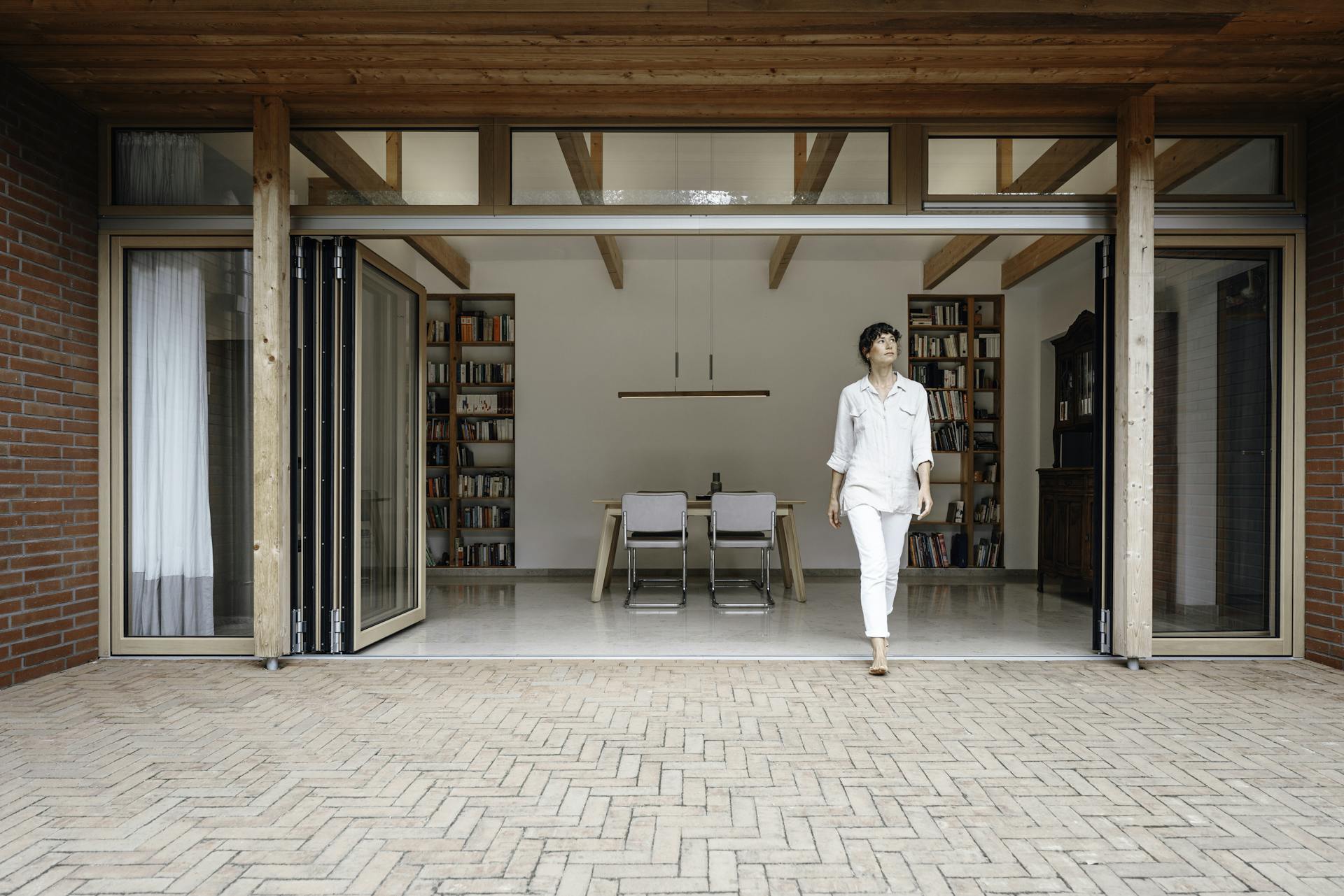 A lady walking through opened timber bi-fold doors