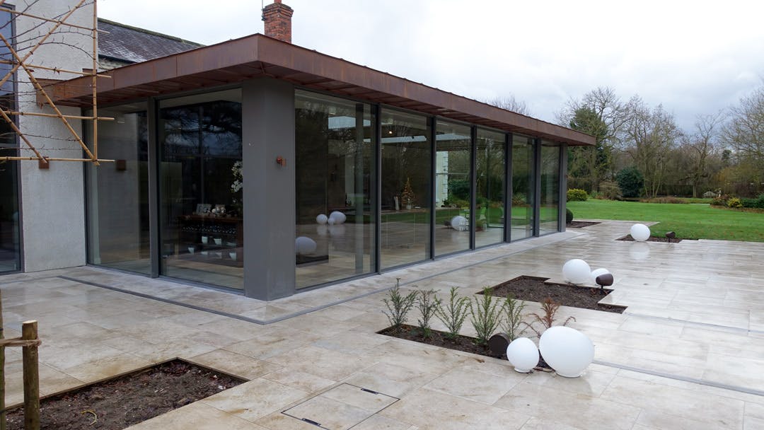 Luxury home extension with oversized sliding glass doors viewed from outside