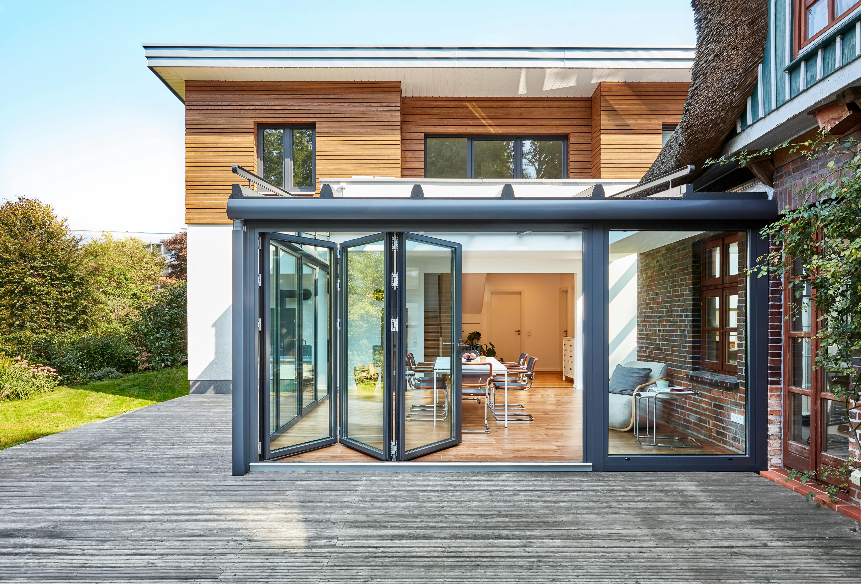 glass extension with bifolding doors on timber and white brick house