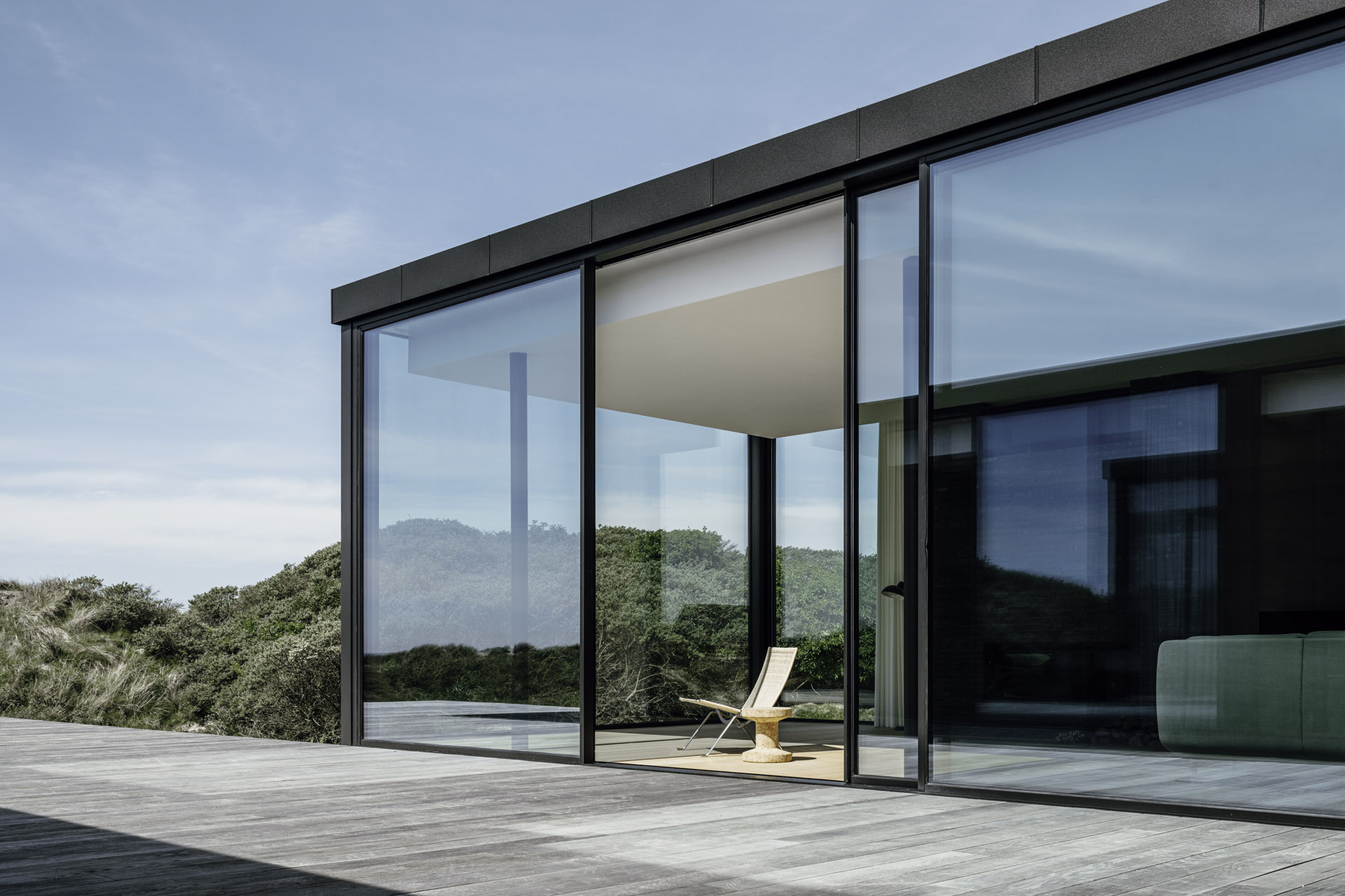 deckchair dwarfed by huge sliding doors at modern property on the beach