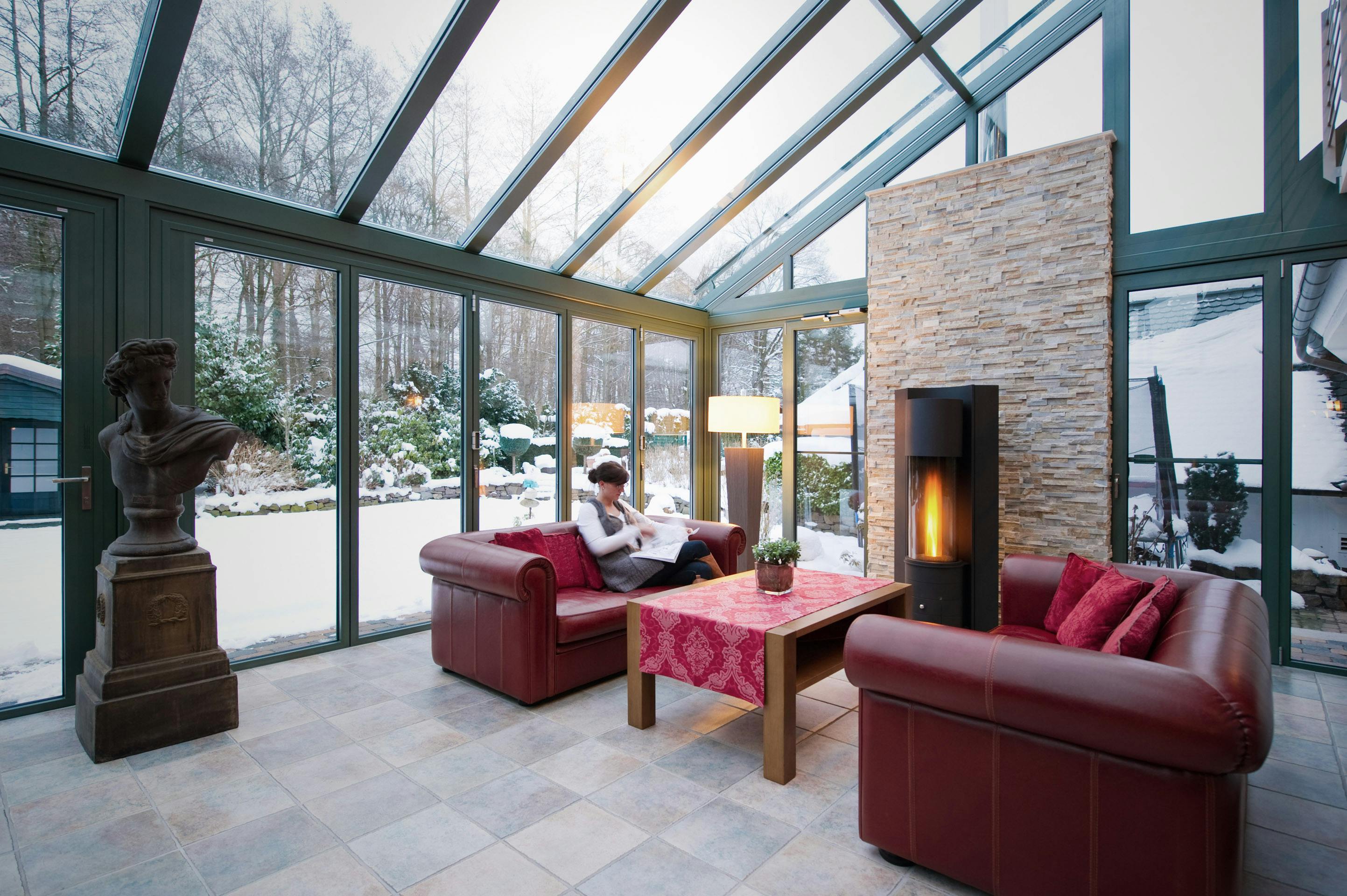 Lady reading on a a red leather sofa with snowy weather outside 