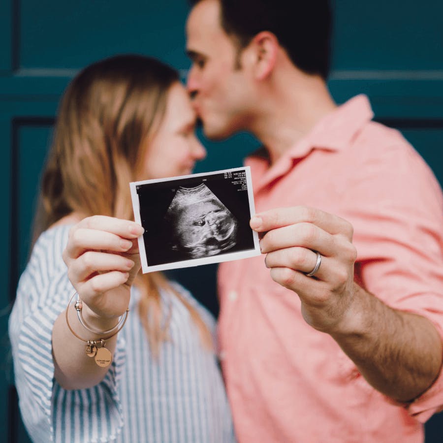 Casal mostrando foto do ultrassom do filho que está na barriga da mãe