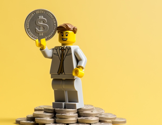 LEGO character holding coin and standing on the coins mountain