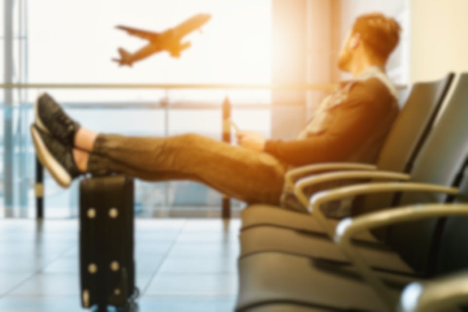 barbat care asteapta avionul pentru a pleca intr-o vacanță în Europa cu bani puțini