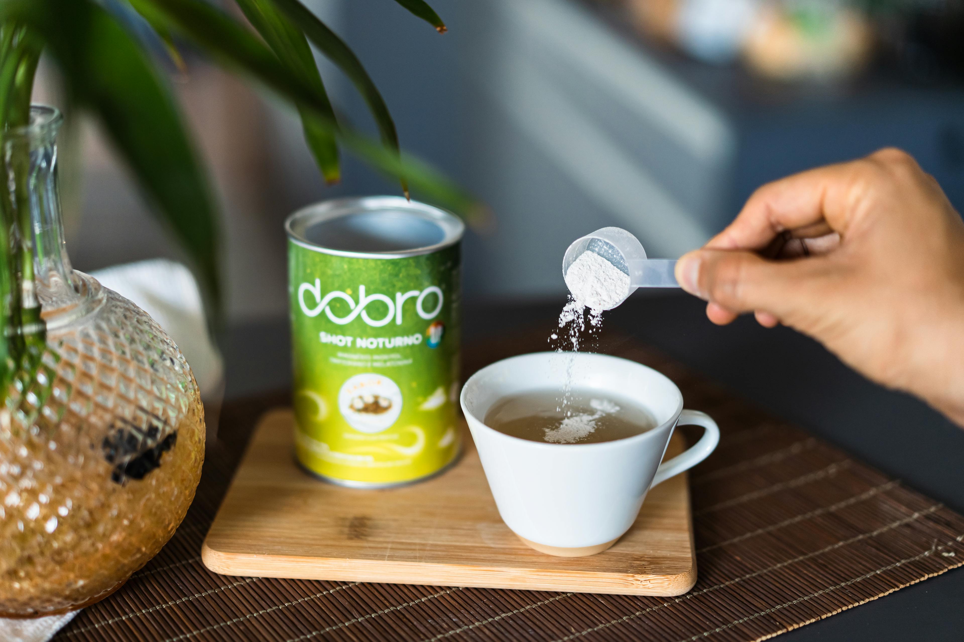 Pessoa preparando o shot noturno da dobro em uma xícara de chá