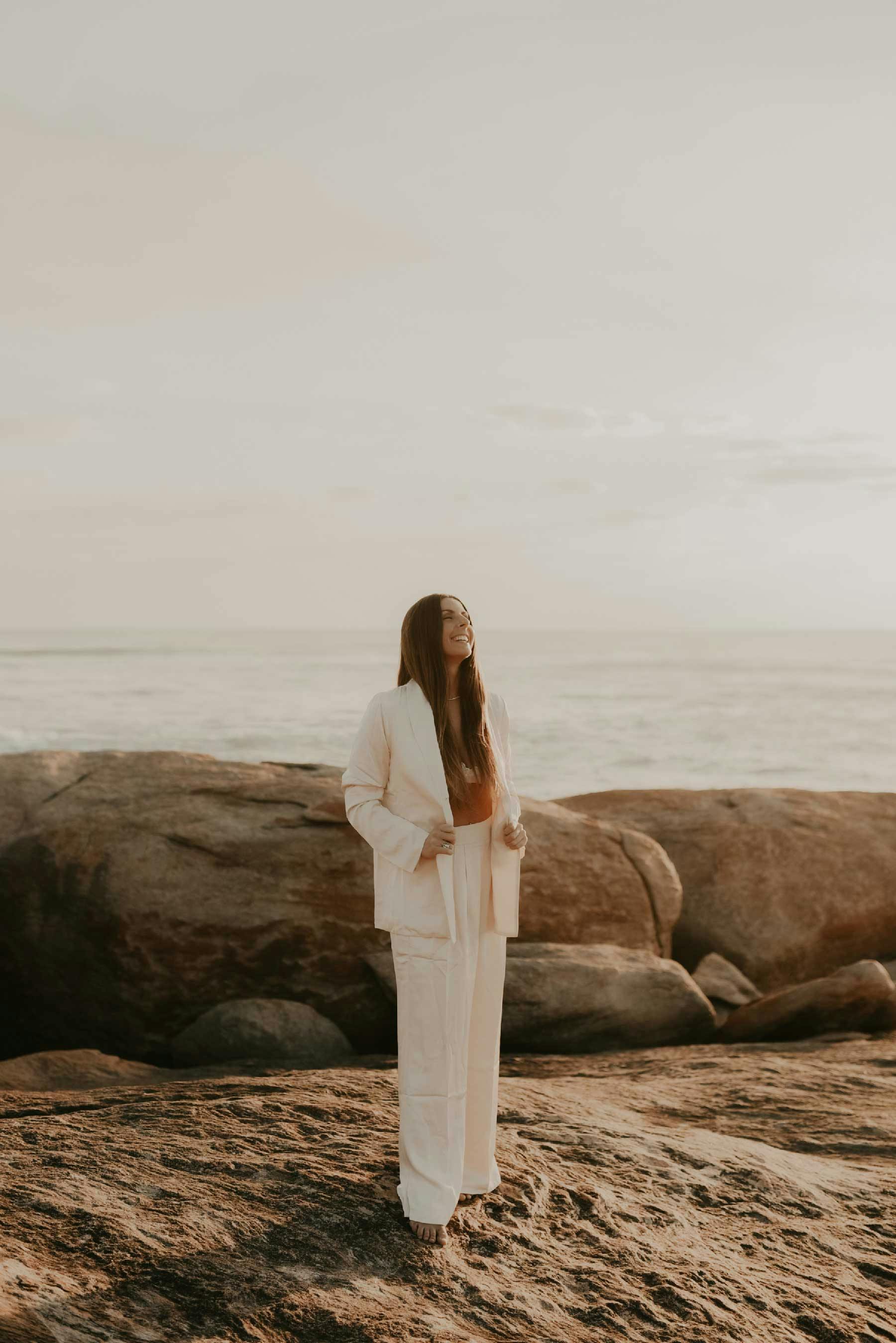 Our founder standing on rocks by the ocean, smiling