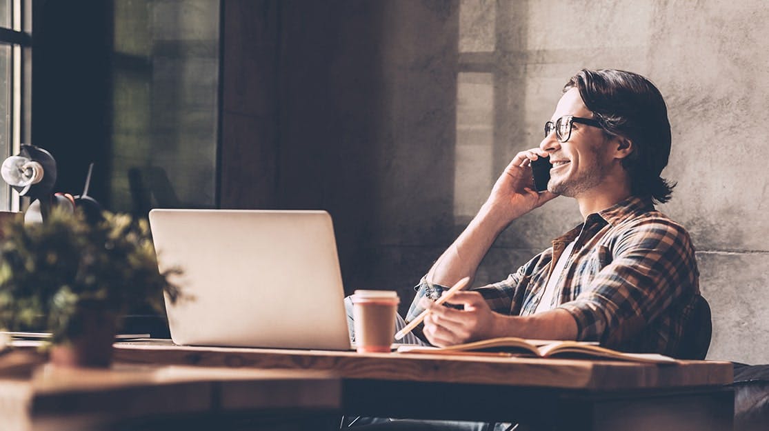 Man in small office on mobile phone