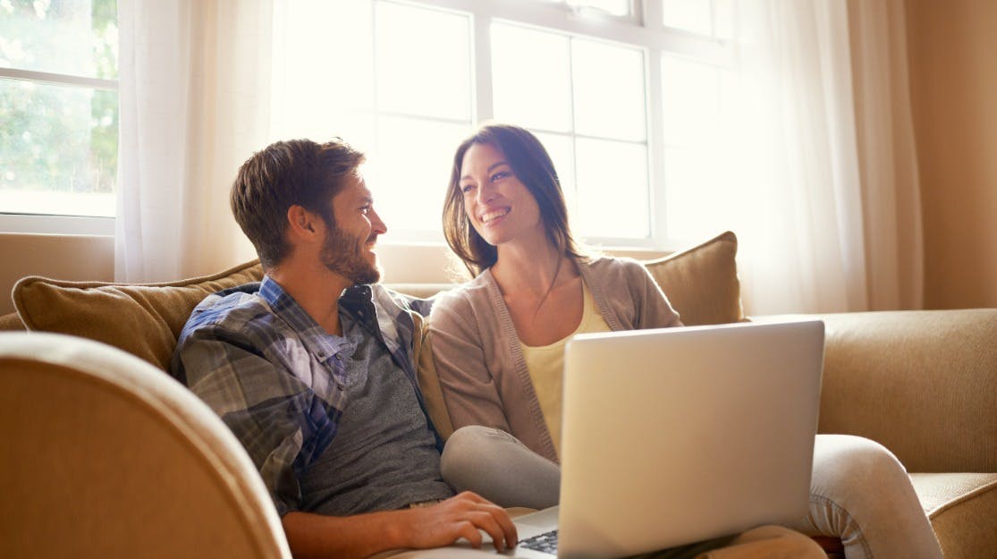 man and woman on couch with laptop