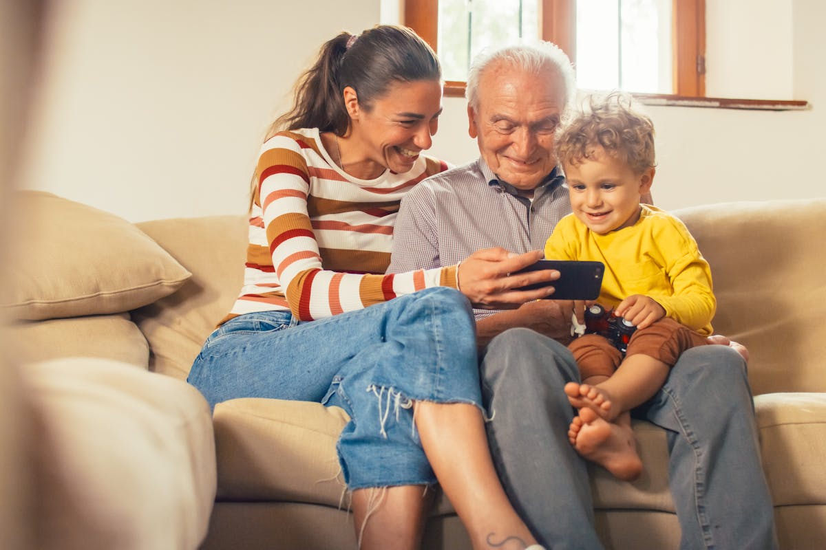 Family, mother grandfather and child looking at content on a phone