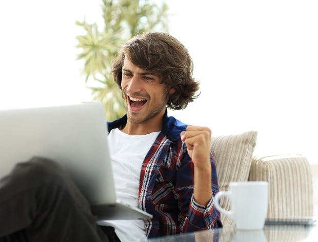 Happy young man looking at laptop