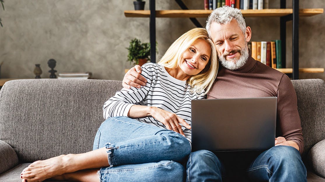 Man and Woman sitting on couch looking at computer