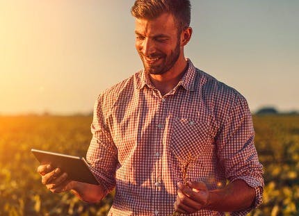 Man standing in a field with a tablet