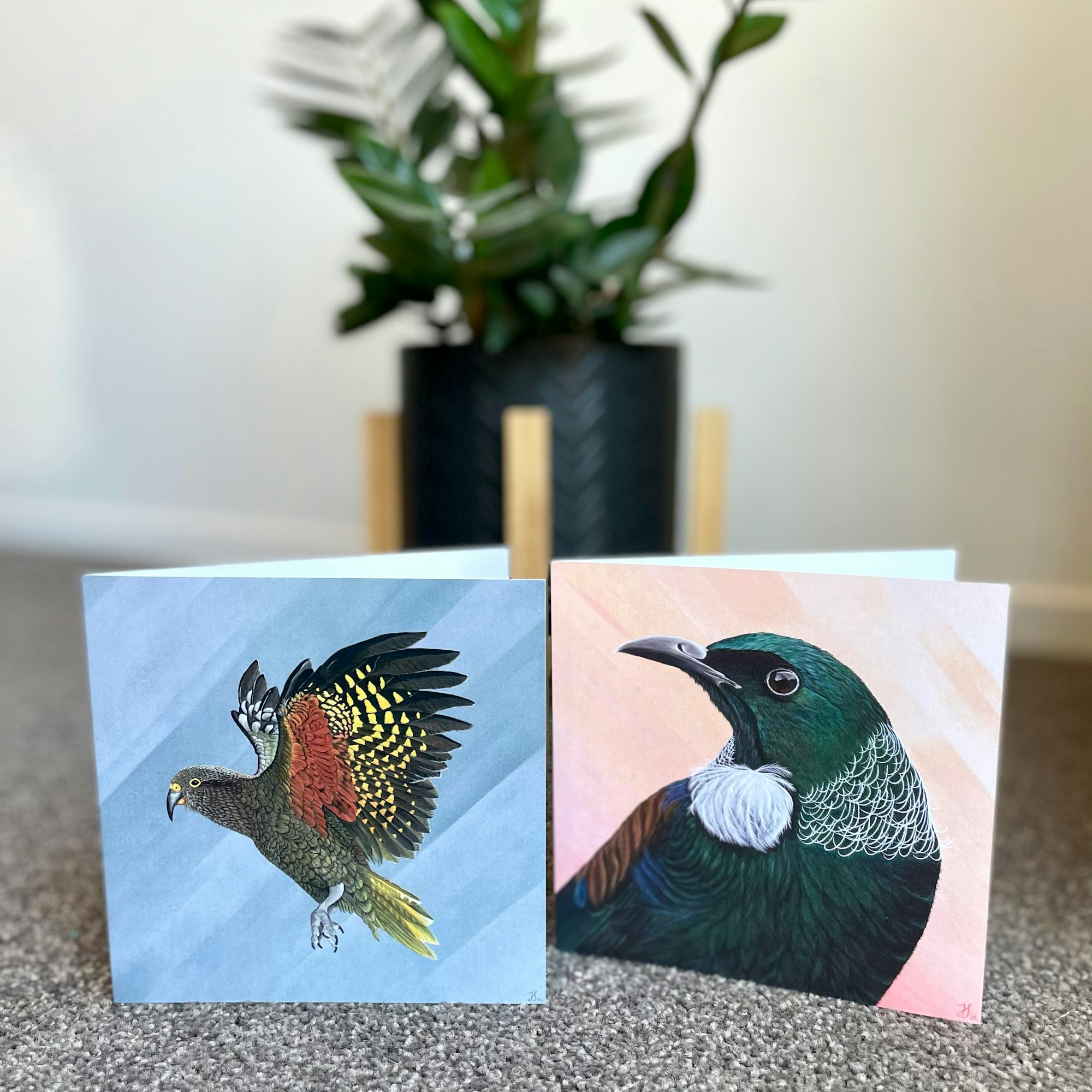 Beautiful greeting cards with a kea bird taking flight and a tui on an abstract background.