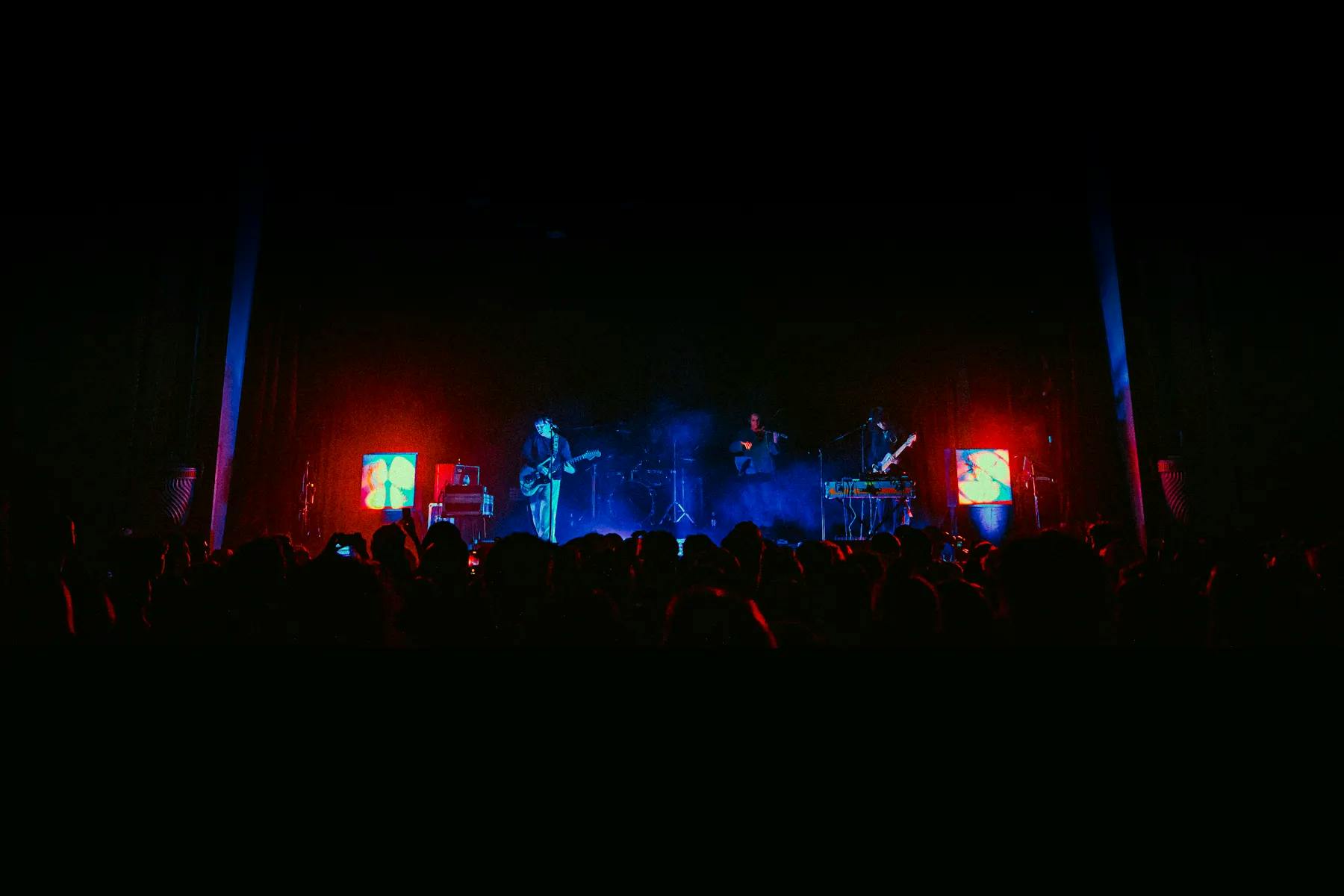 Photo of stage at band Jadu Heart concert. Blue stage lighting, red scenic lantern on each side of stage