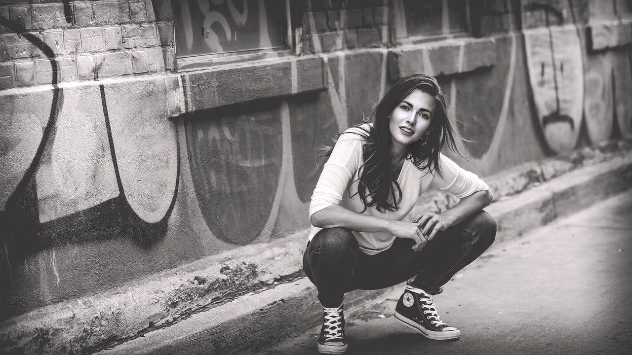 About You Mode Trends Frau kniet vor Graffiti Wand