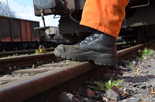 Arbeiter trägt Arbeitsstiefel zwischen Abstellgleisen