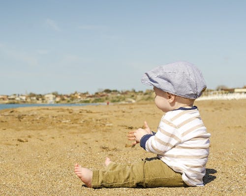 Ernstings family Jungenmode Kleiner Junge sitzt am Strand