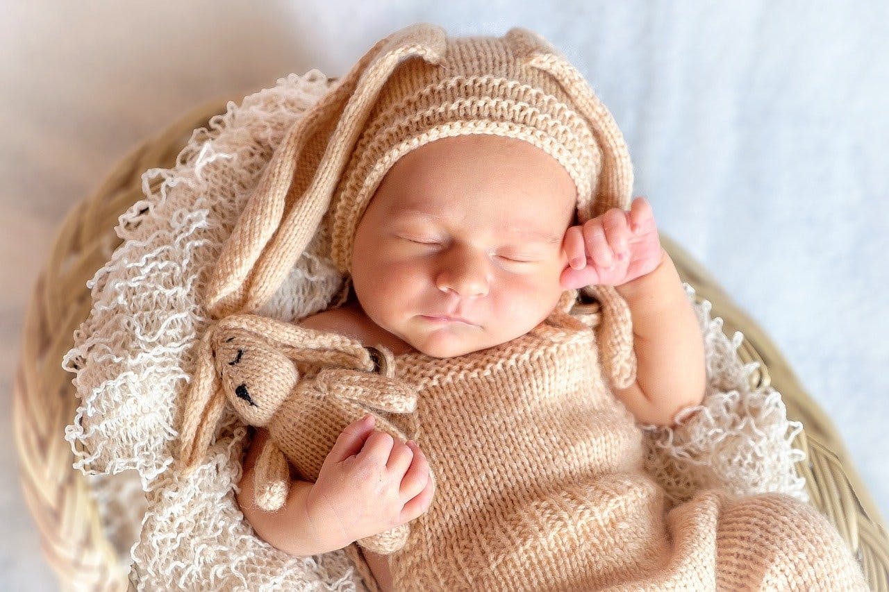 milquino Gutschein Schlafendes Baby in Hasenkostüm mit Hasen-Teddy im Arm