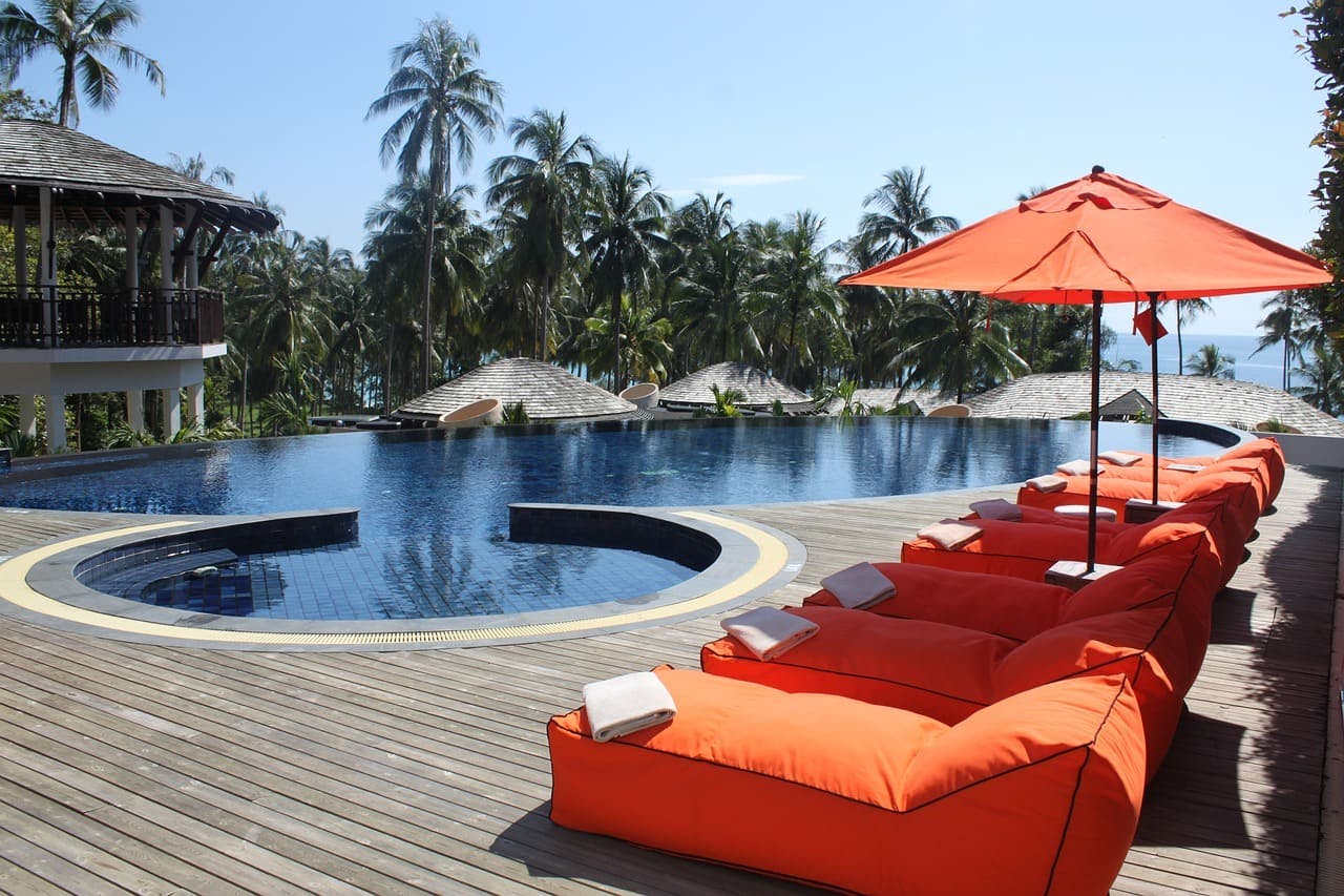 Hotels.com_Pool Orangene Polster am Pool mit Palmen