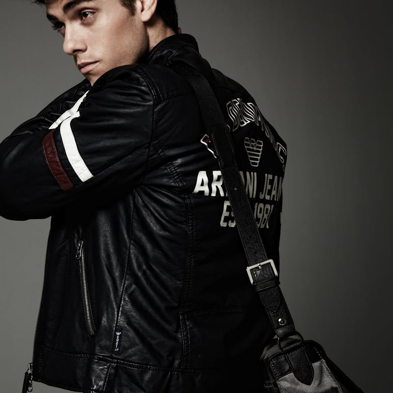 Ein Mann mit schwarz-weißer Jacke und Tasche schaut zur Seite.